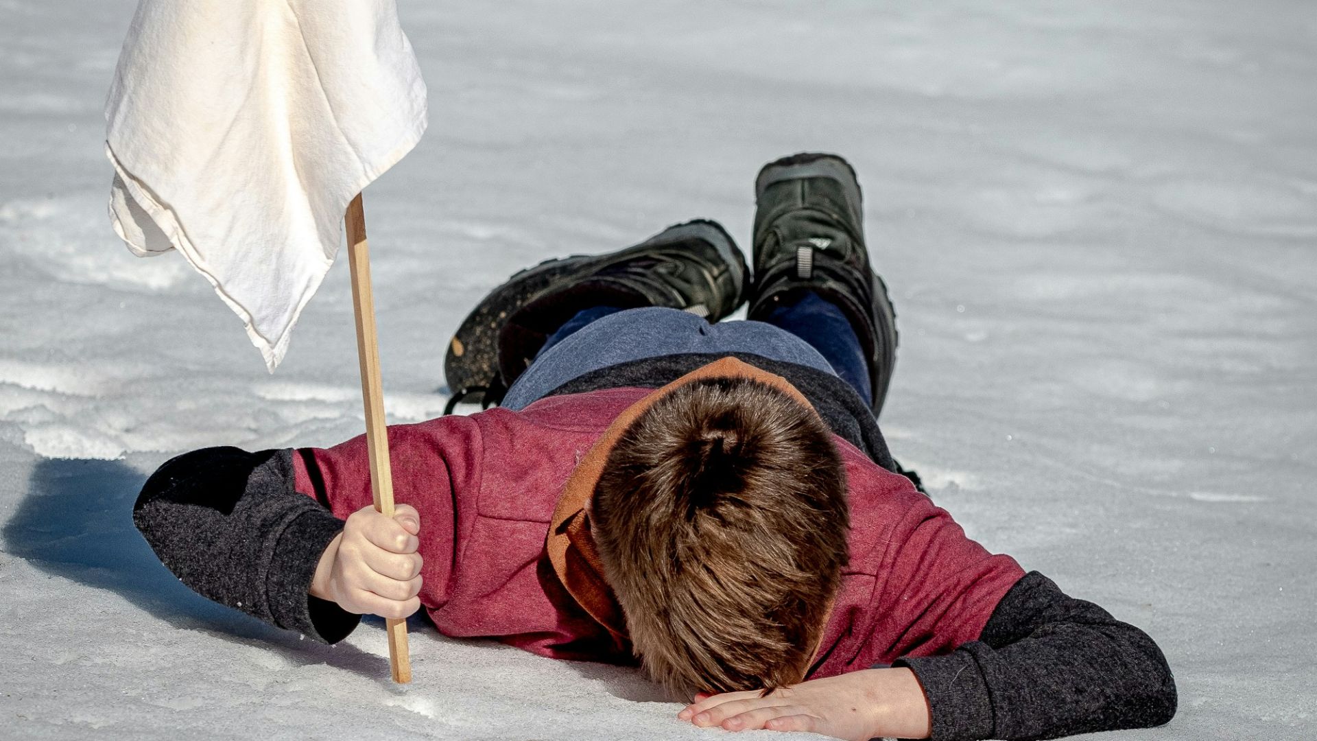 woman in black jacket lying on white snow