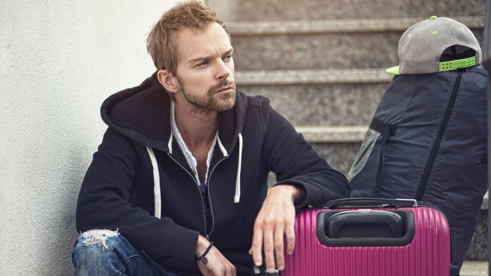 a man sitting next to a purple suitcase