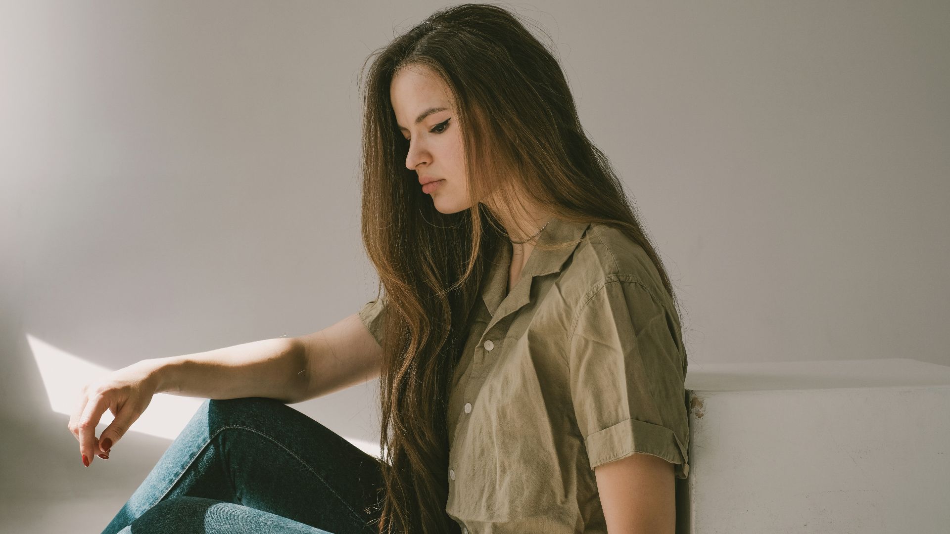 a woman sitting on the floor looking at a laptop