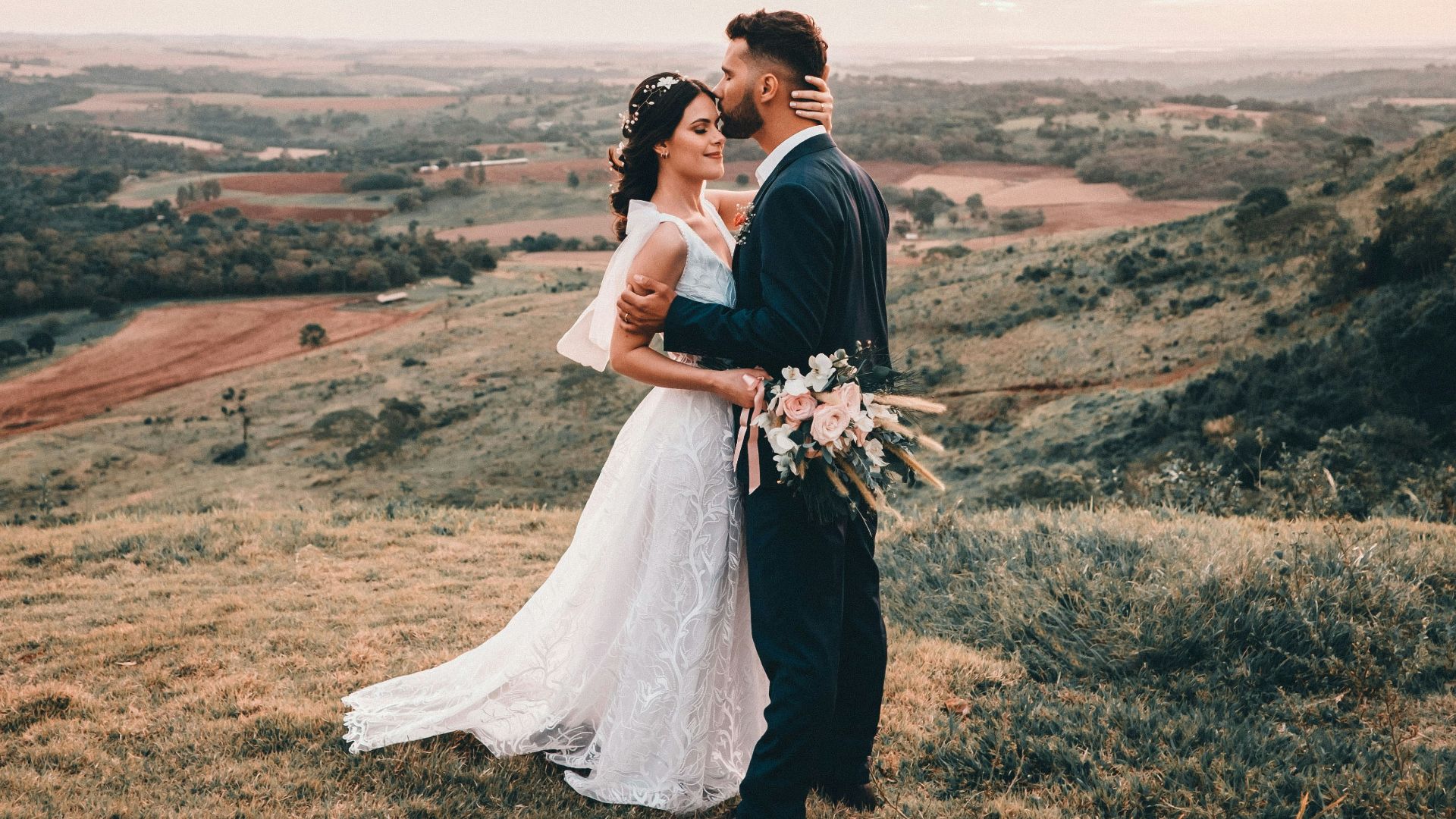 man and woman kissing on brown grass field during daytime
