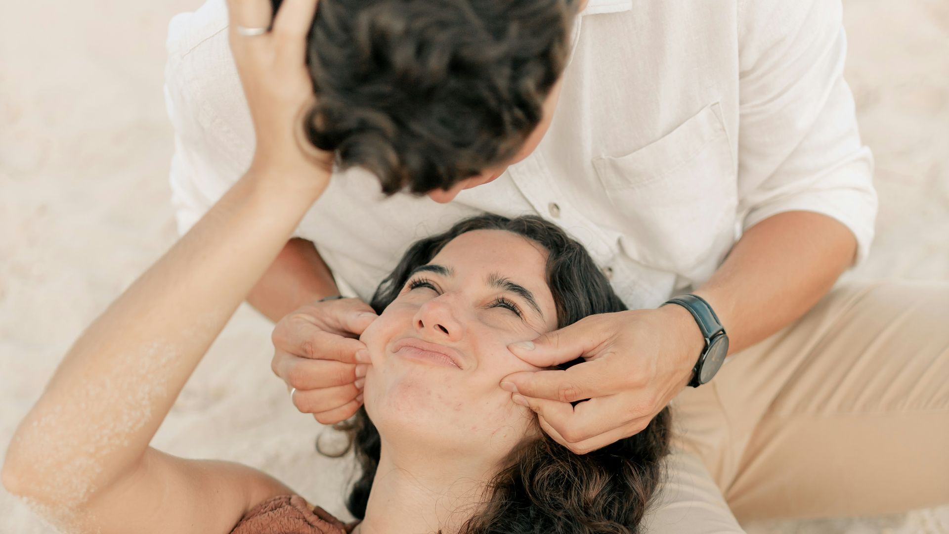 A woman laying on the beach with a man