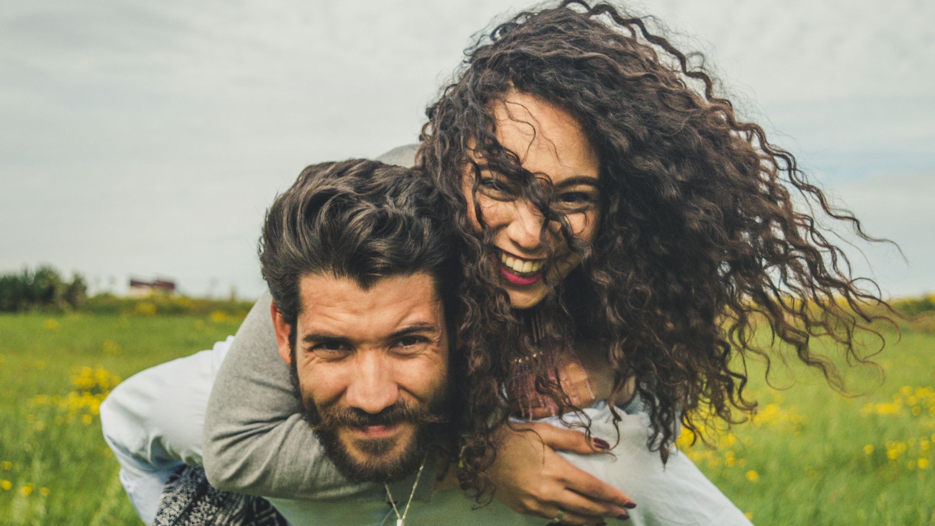 woman riding on man's back on green field