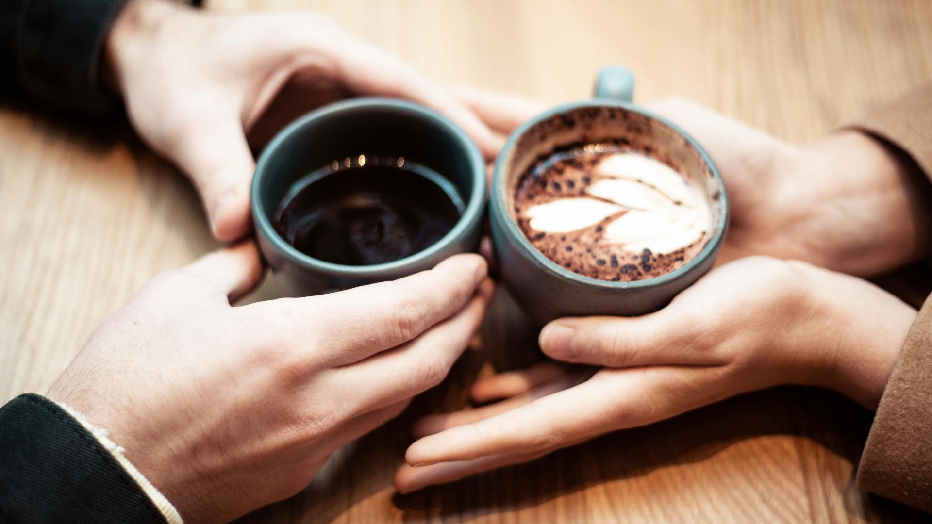 two person holding ceramic mugs with coffee