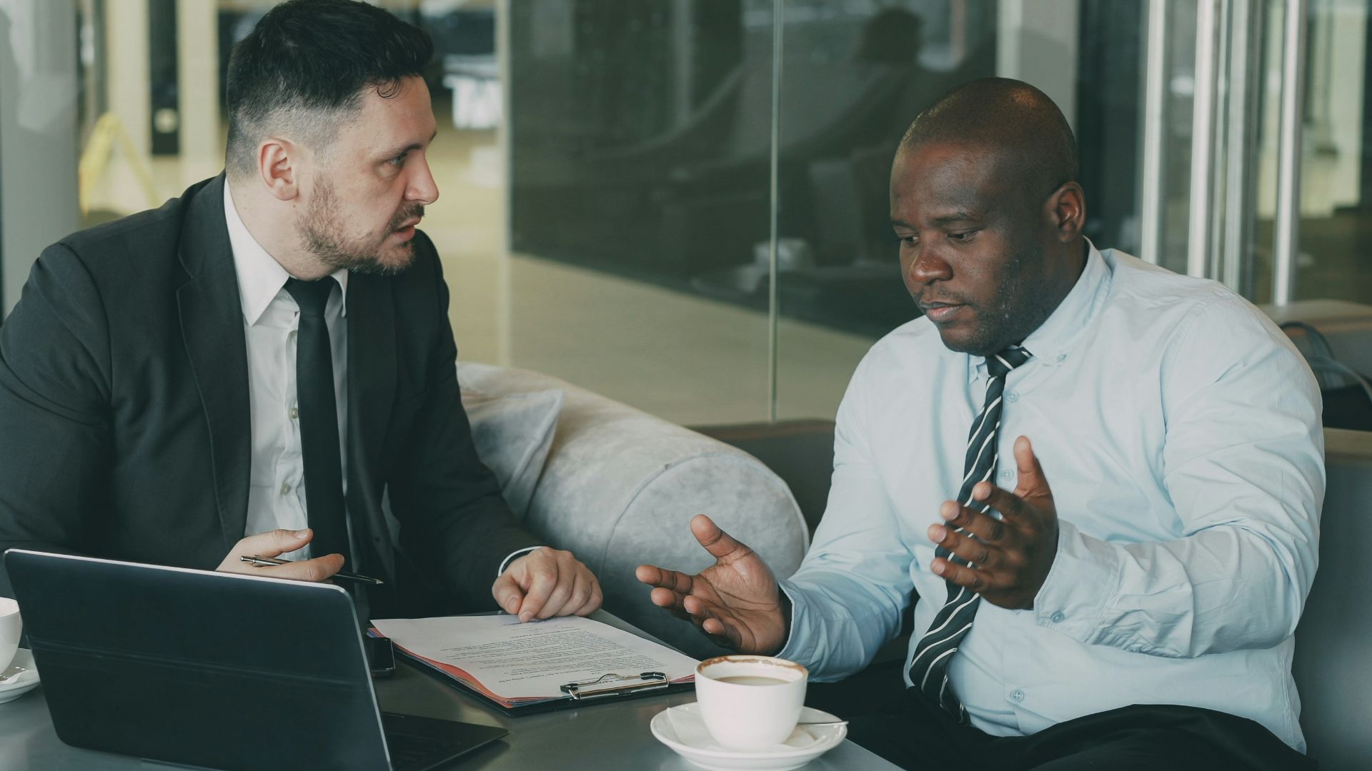 Two businessmen discussing documents at a table.