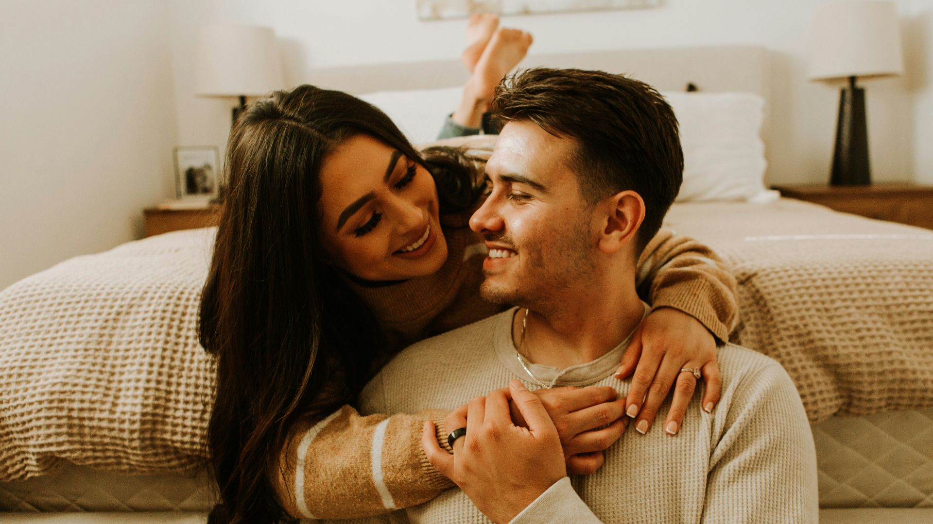 a man and a woman sitting on a bed together