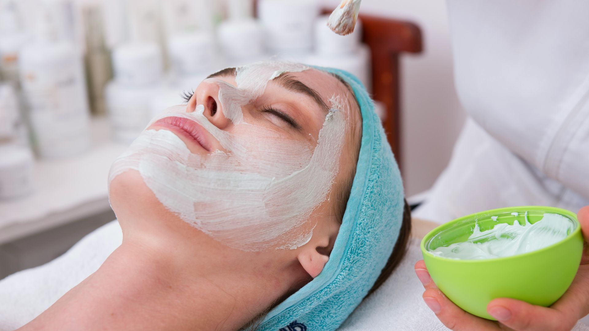woman lying on blue towel with white cream on face