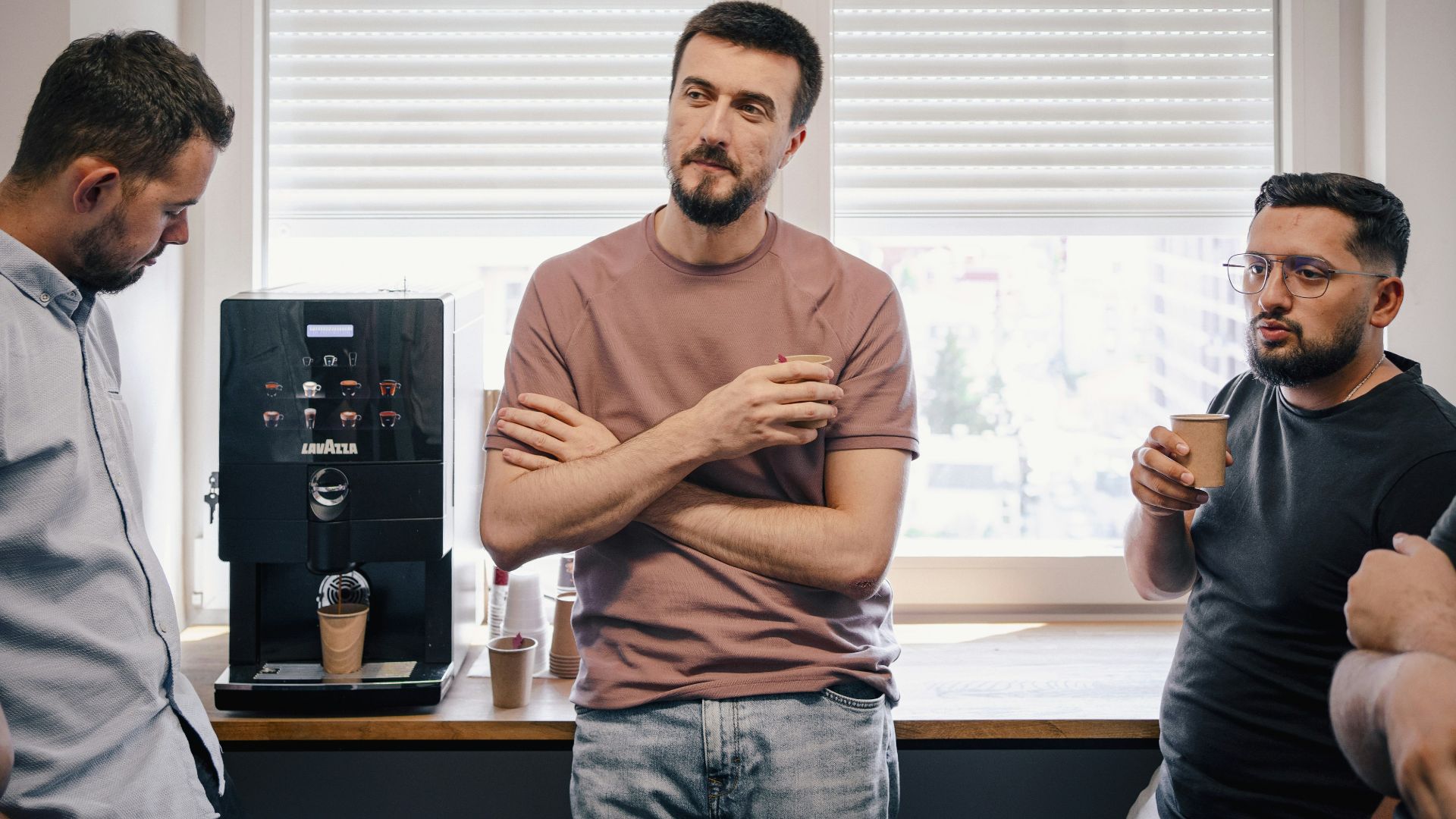 a group of men standing around a coffee machine