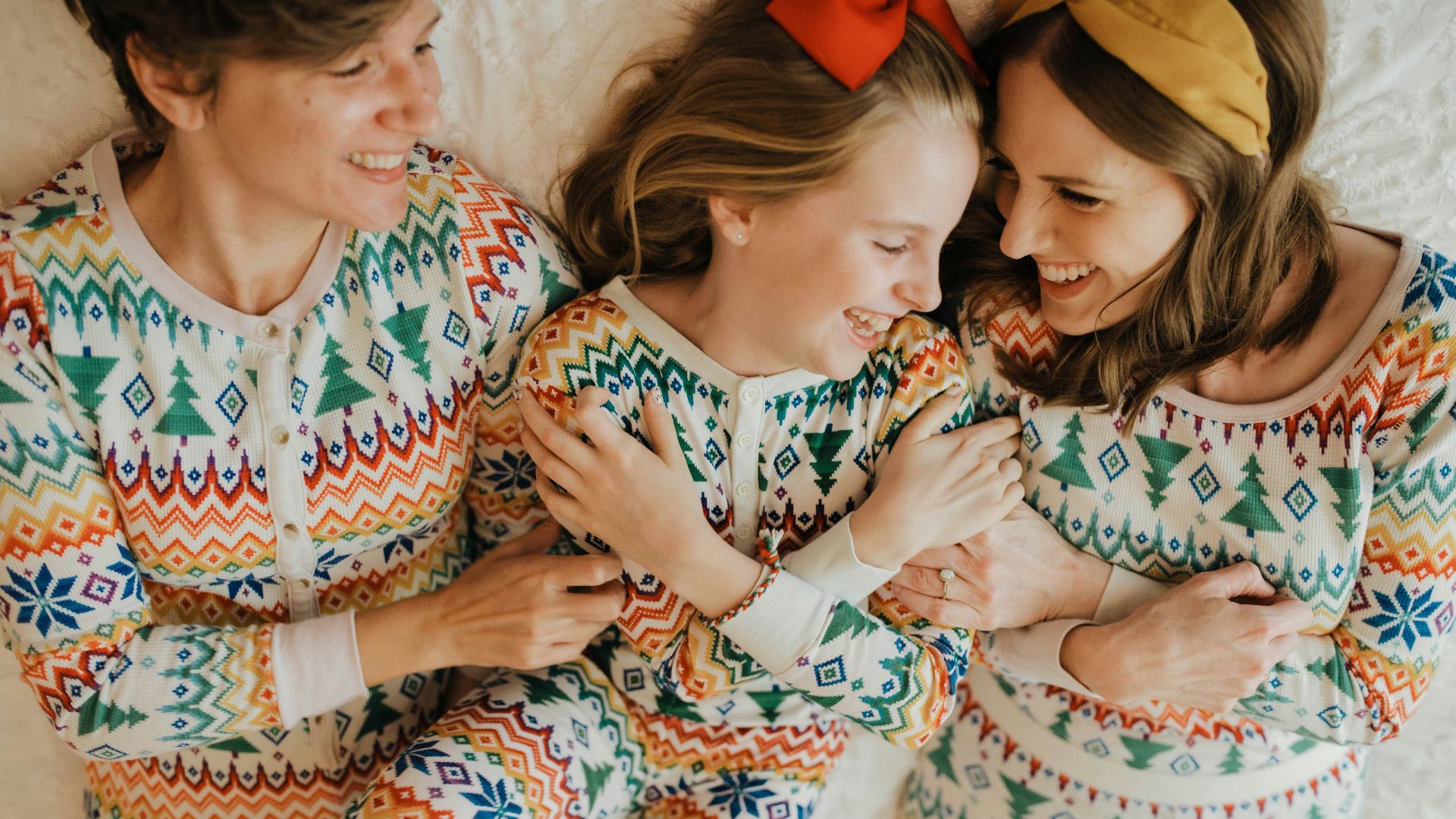 a group of women in colorful pajamas laying on a bed