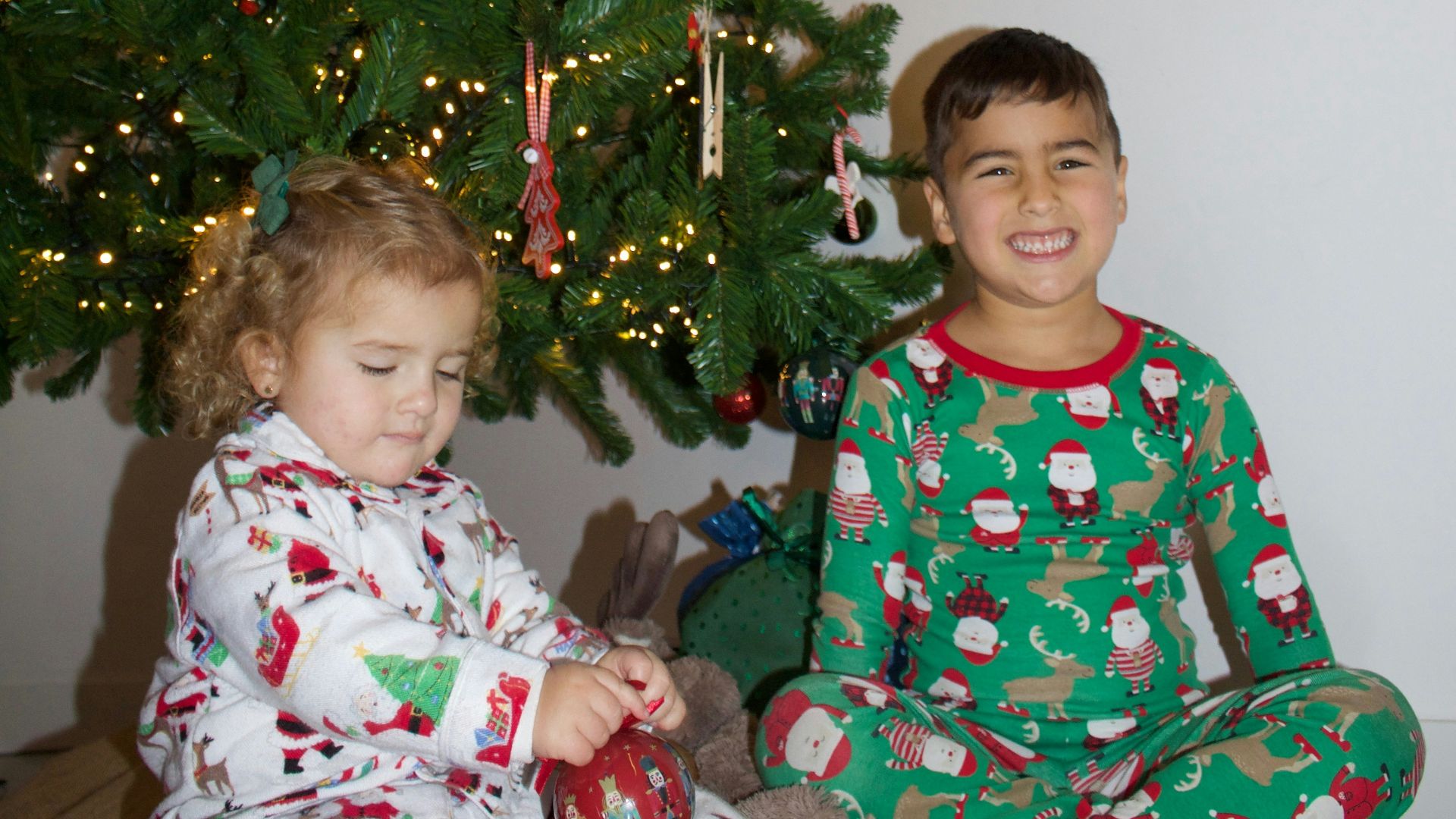 two children sitting in front of a christmas tree