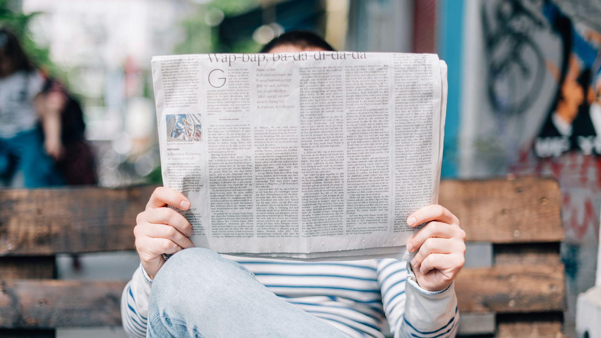 man sitting on bench reading newspaper