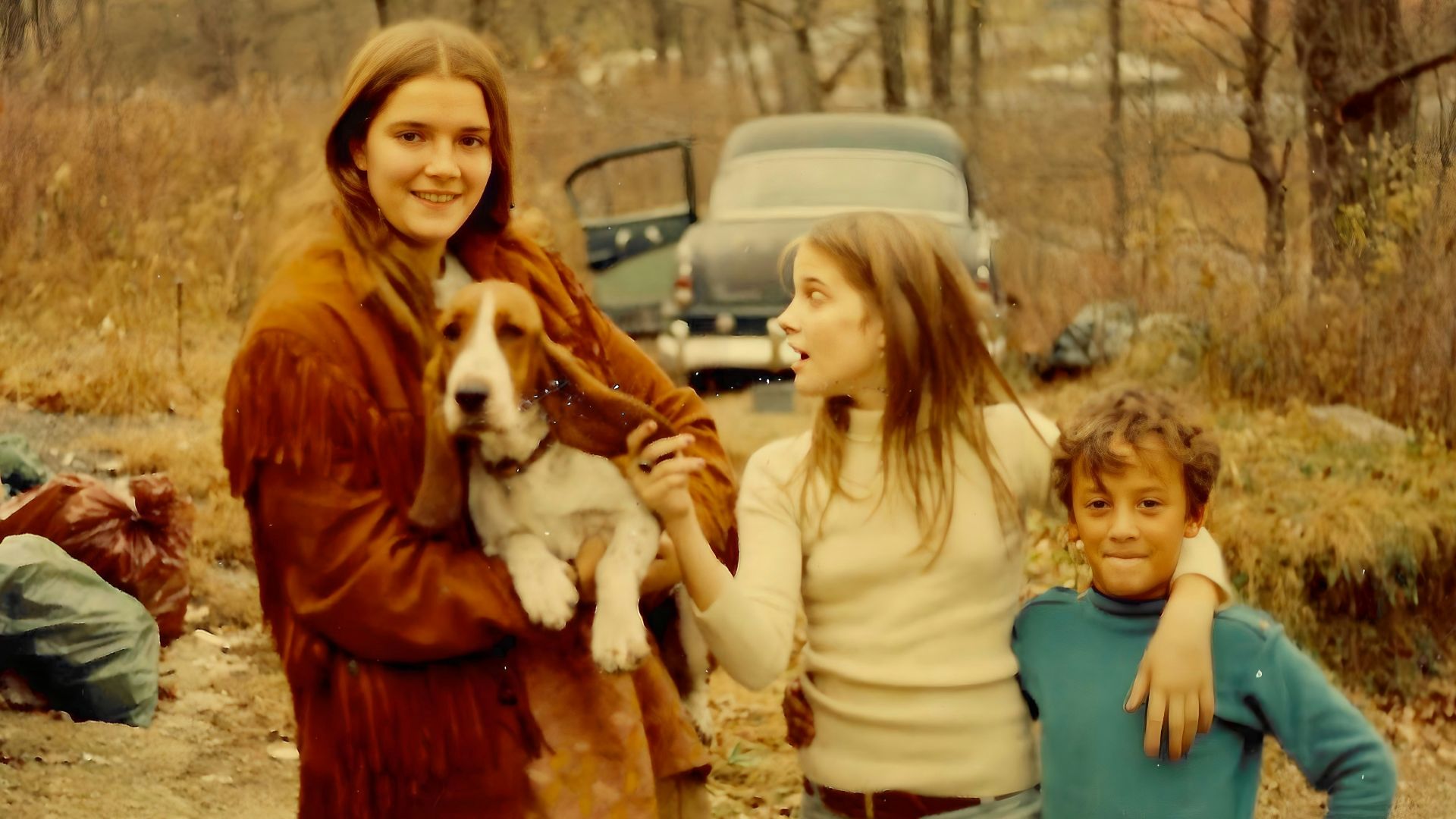 A woman holding a dog standing next to two children