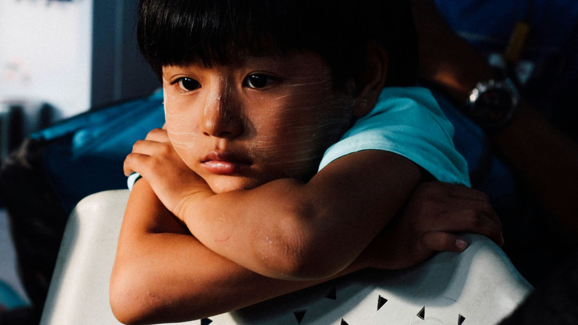 boy leaning on white chair
