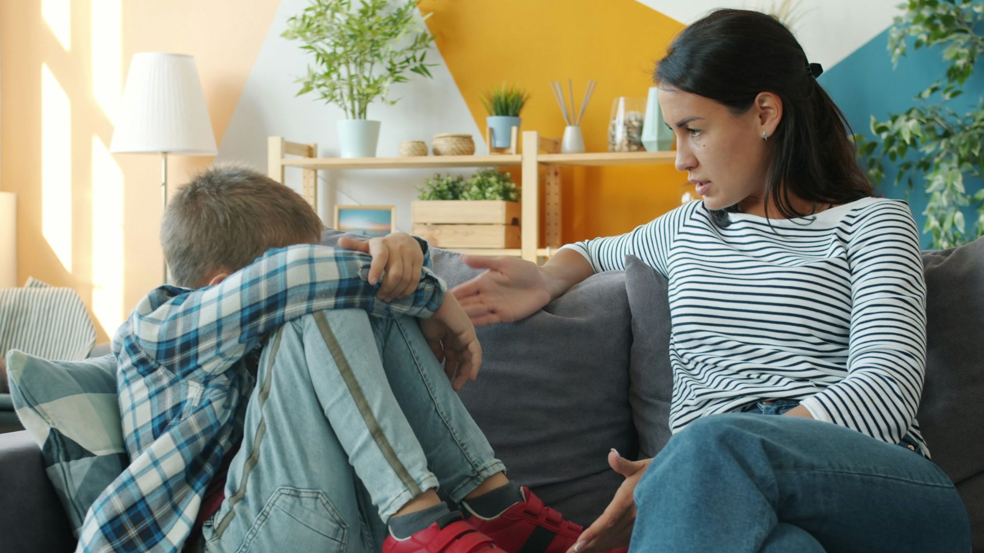 Mother comforts upset child on the sofa