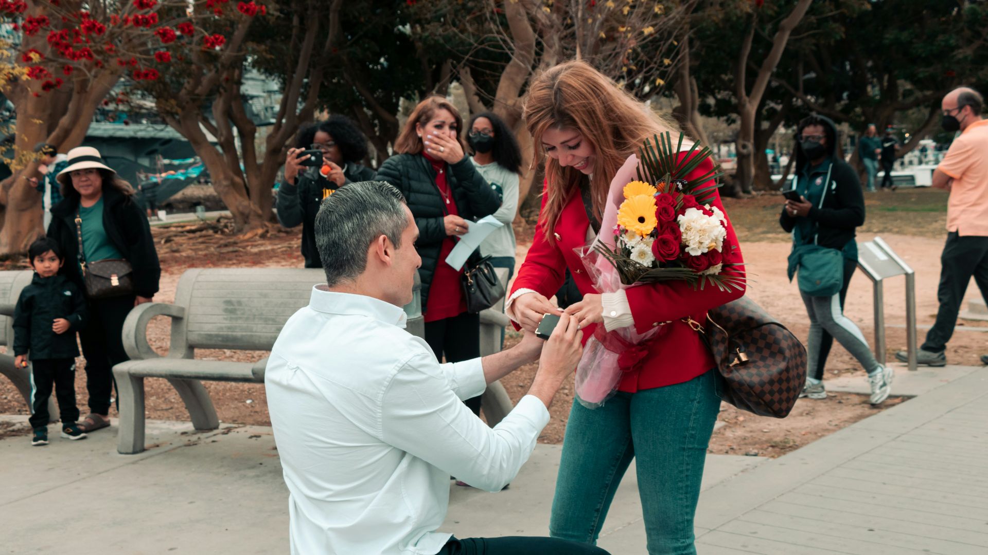 a man kneeling down next to a woman on a bench