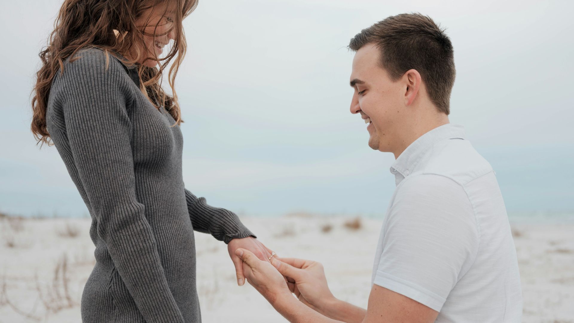a man kneeling down next to a woman on a beach
