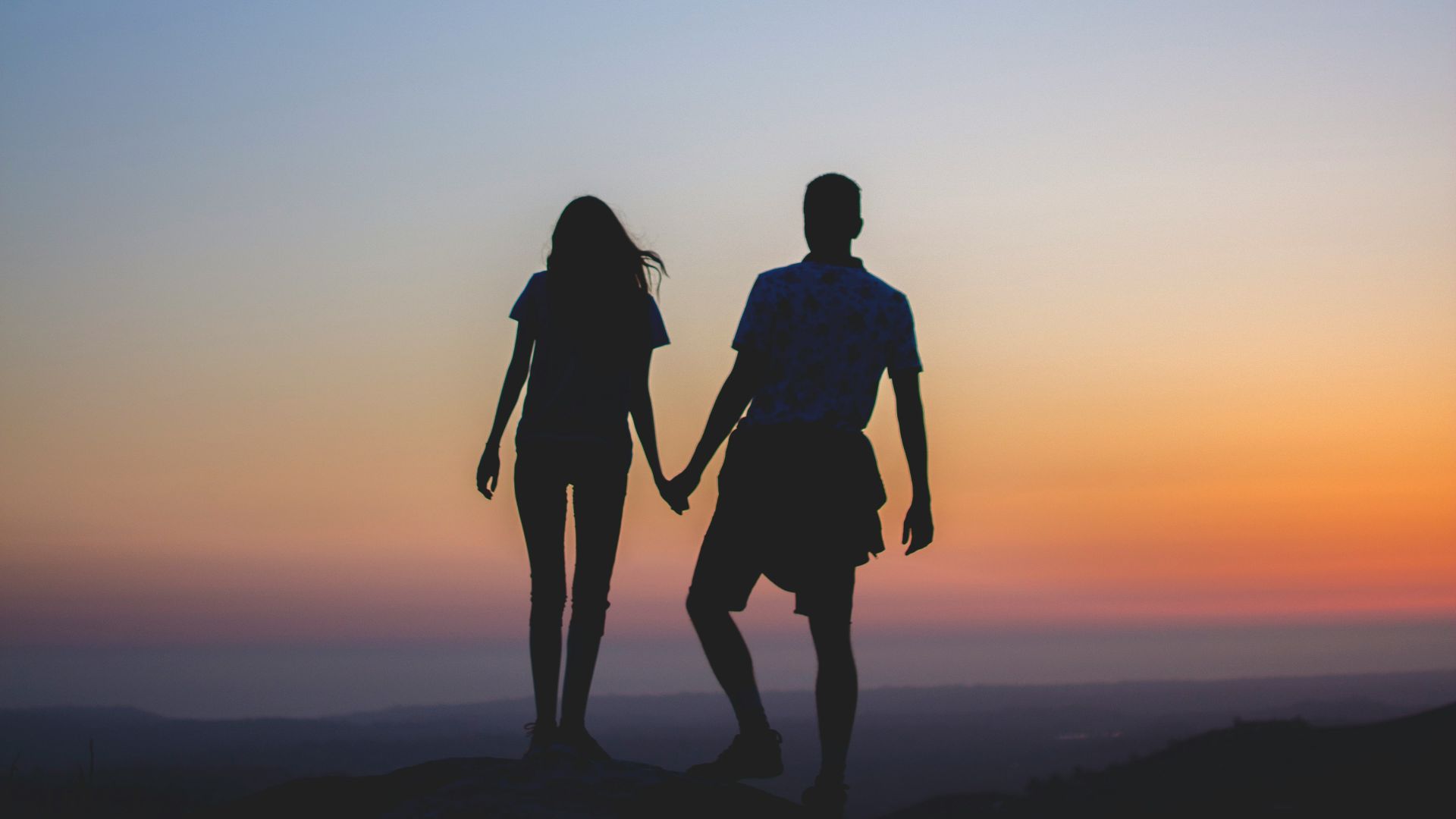 man and woman holding hands in silhouette photography