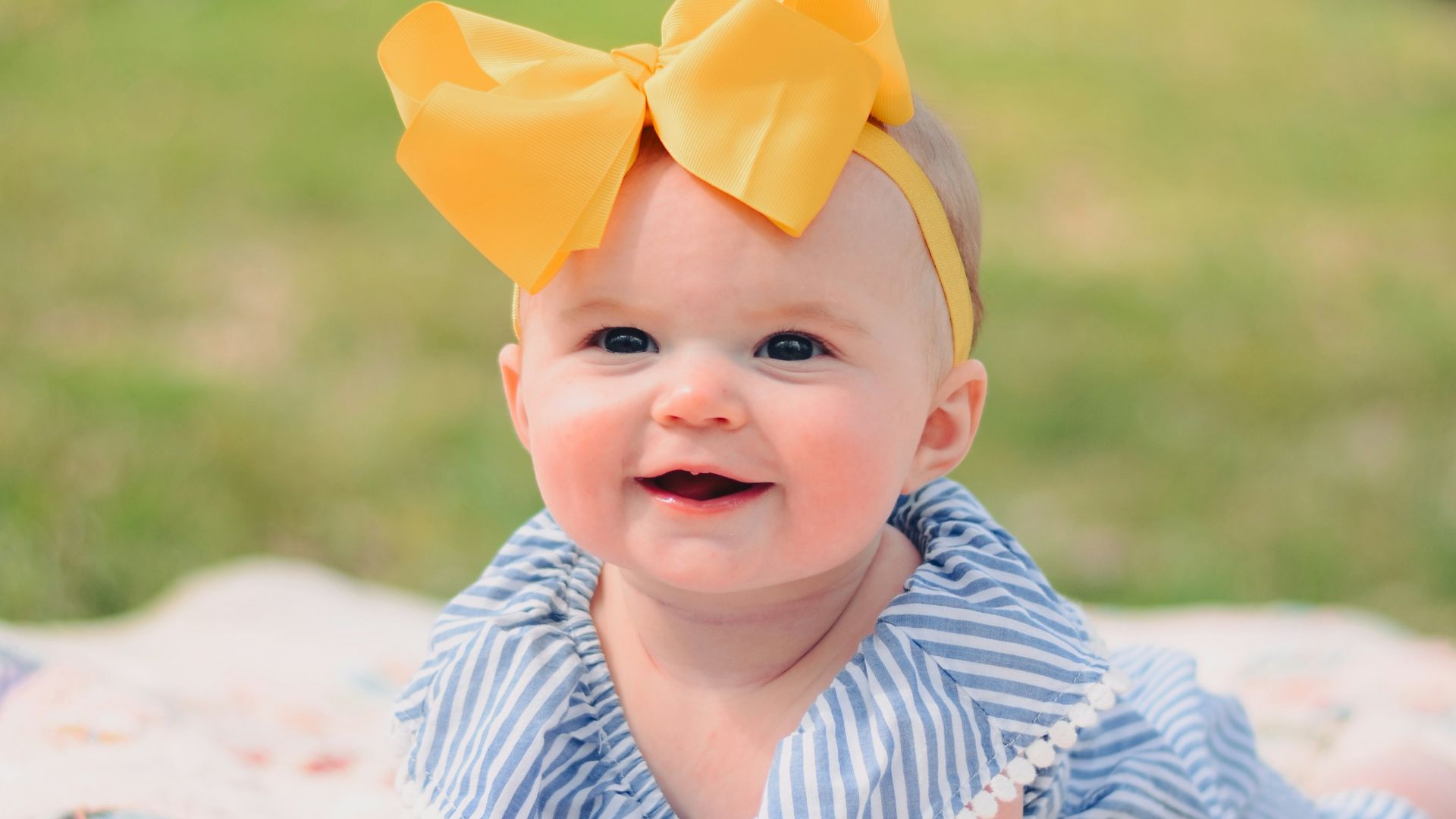 smiling baby lying forward on pink textile