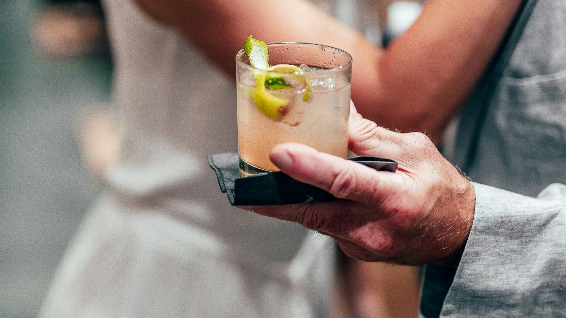 woman in white dress holding drinking glass with yellow liquid