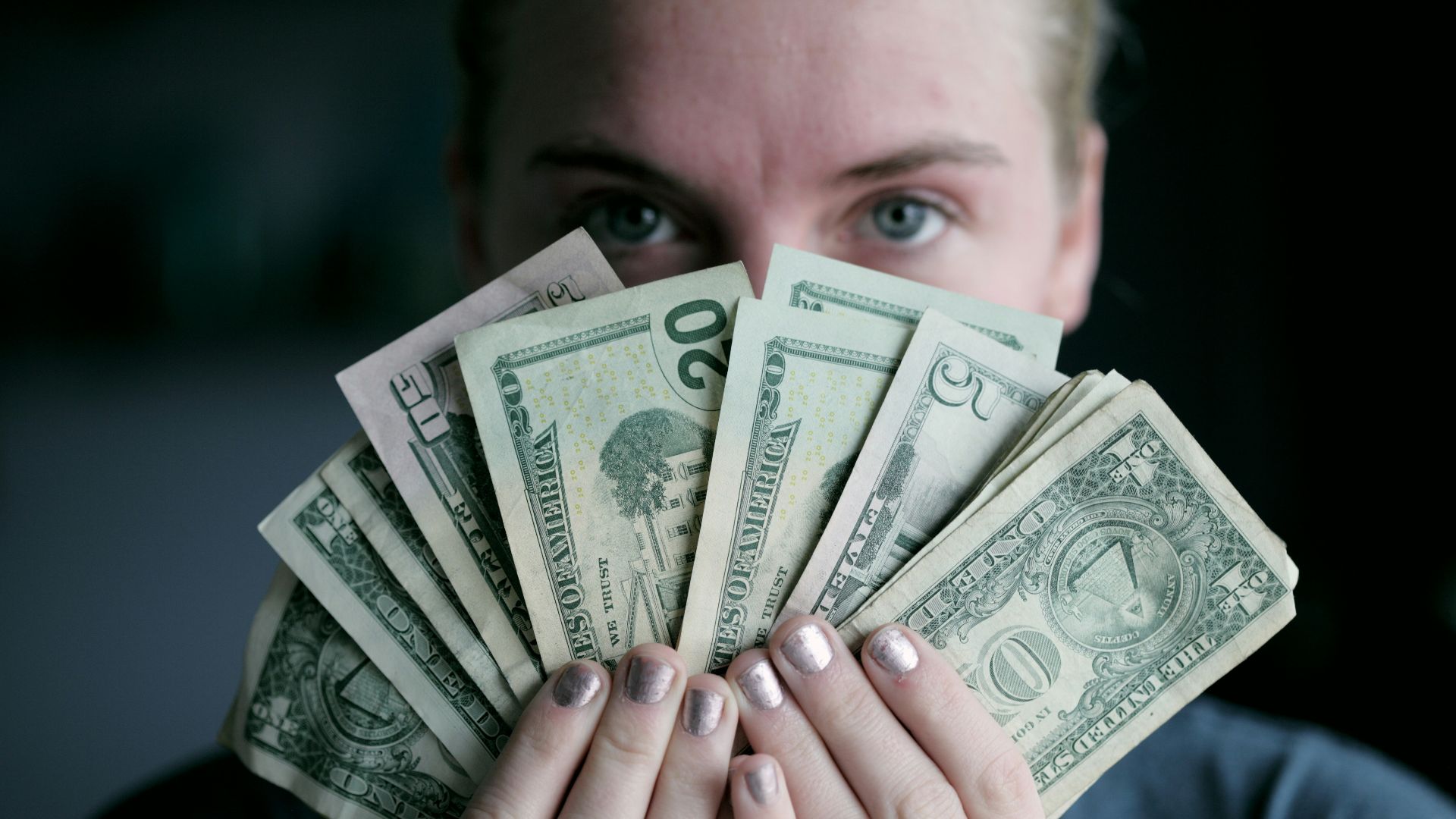 person holding fan of U.S. dollars banknote