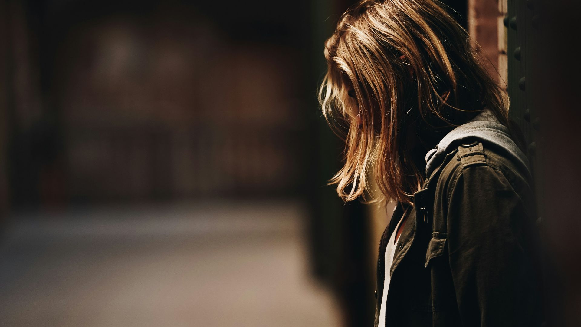 woman leaning against a wall in dim hallway