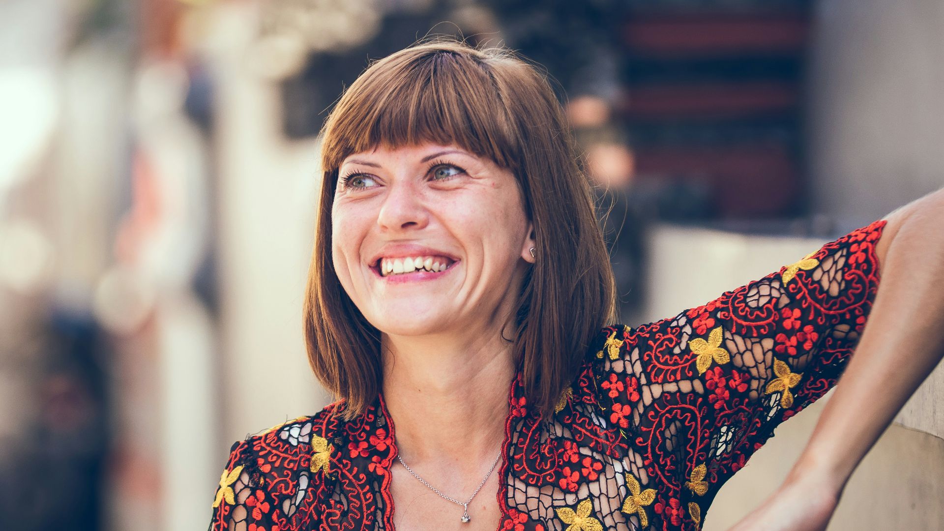 woman in floral-themed cardigan leaning on fence in bokeh photography