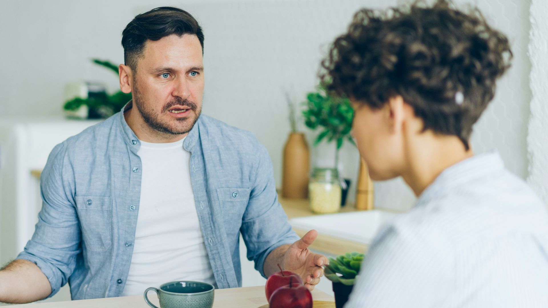 a man sitting at a table talking to a woman