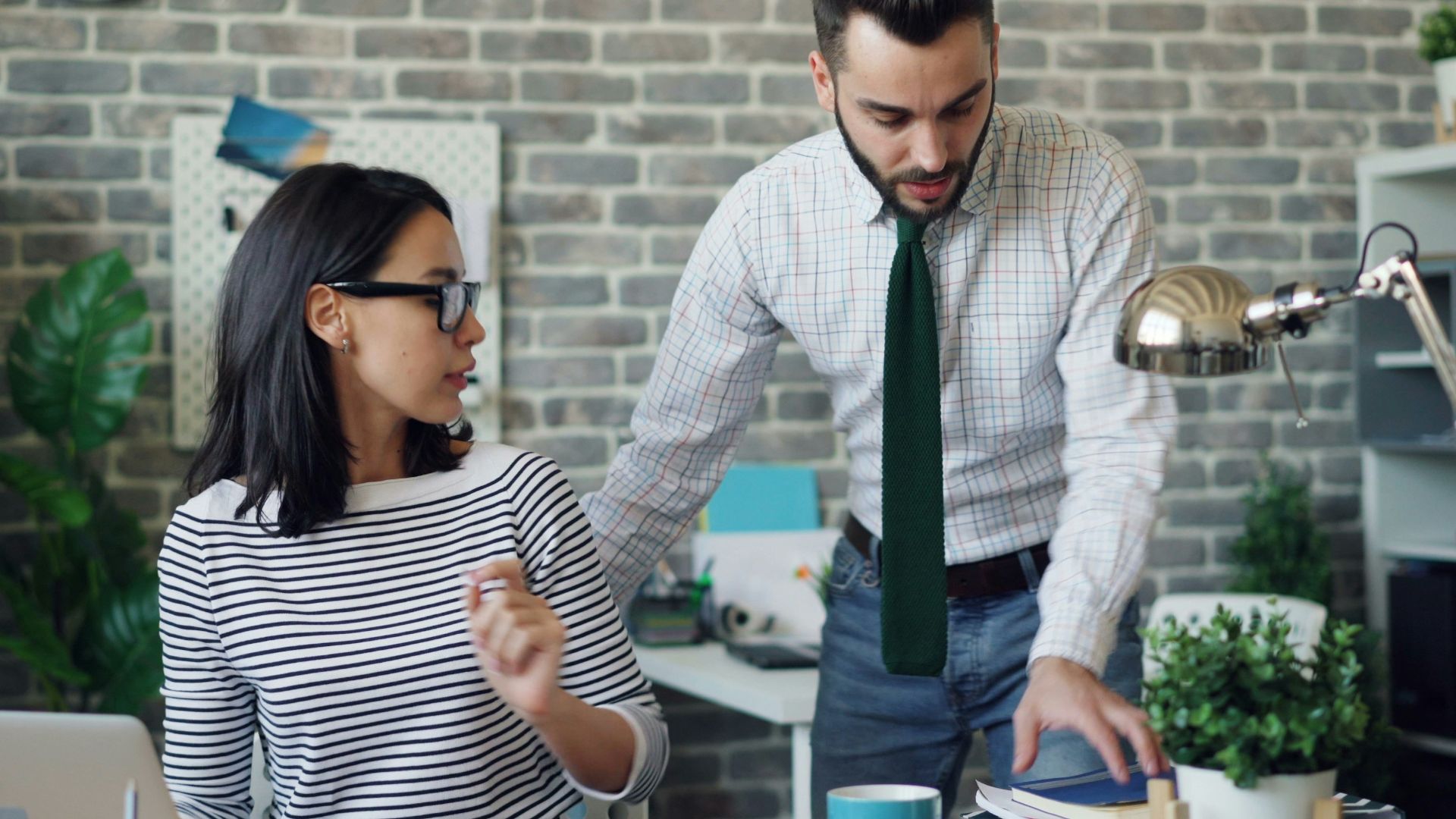 a man and a woman standing in front of a laptop