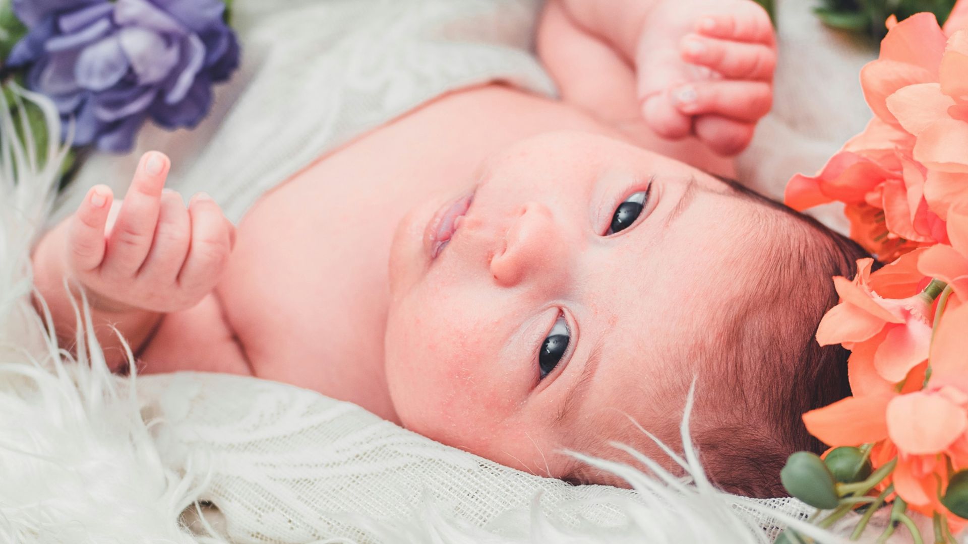 baby lying on white textile