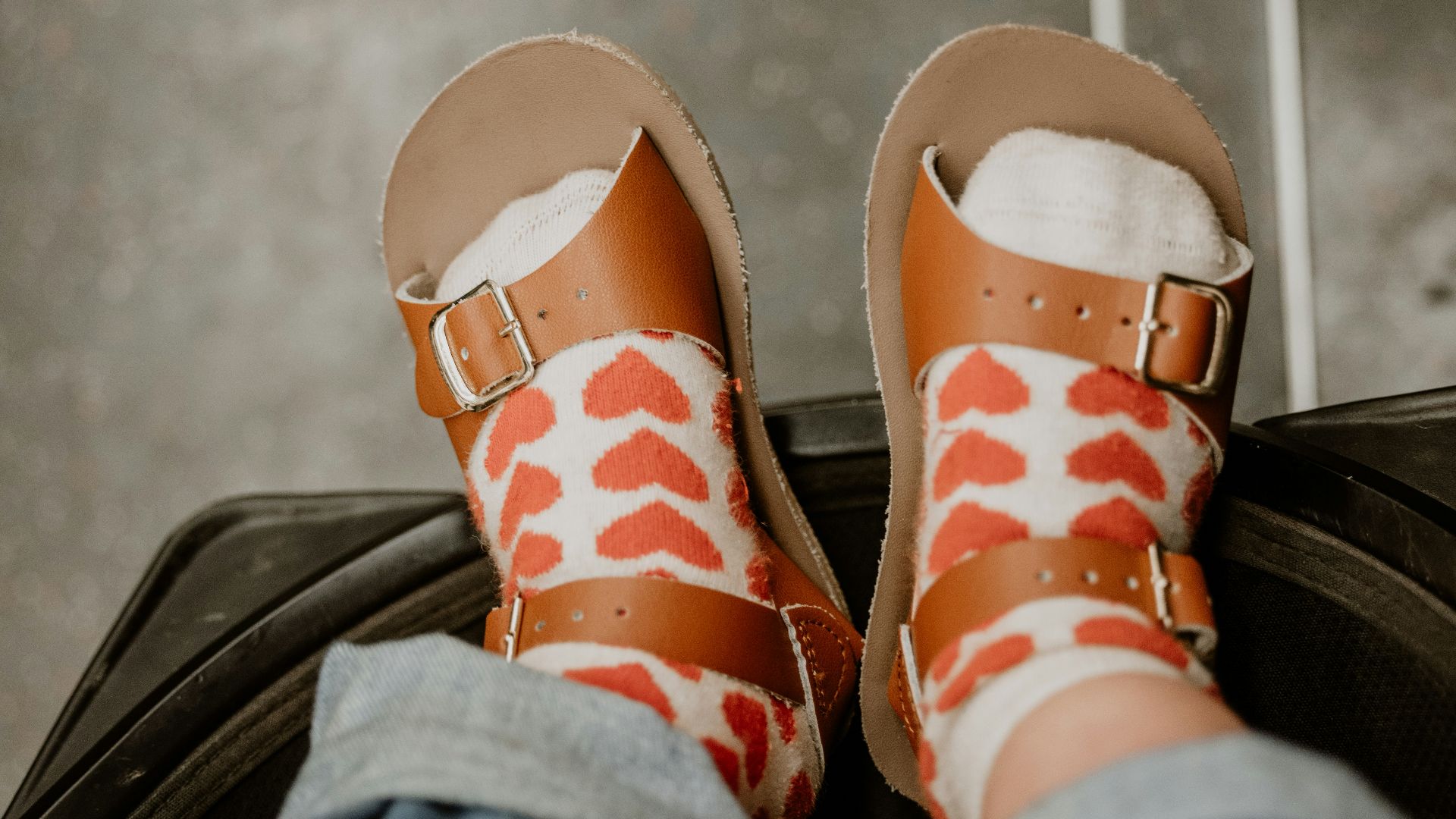 a person's feet in sandals sitting on top of a piece of luggage