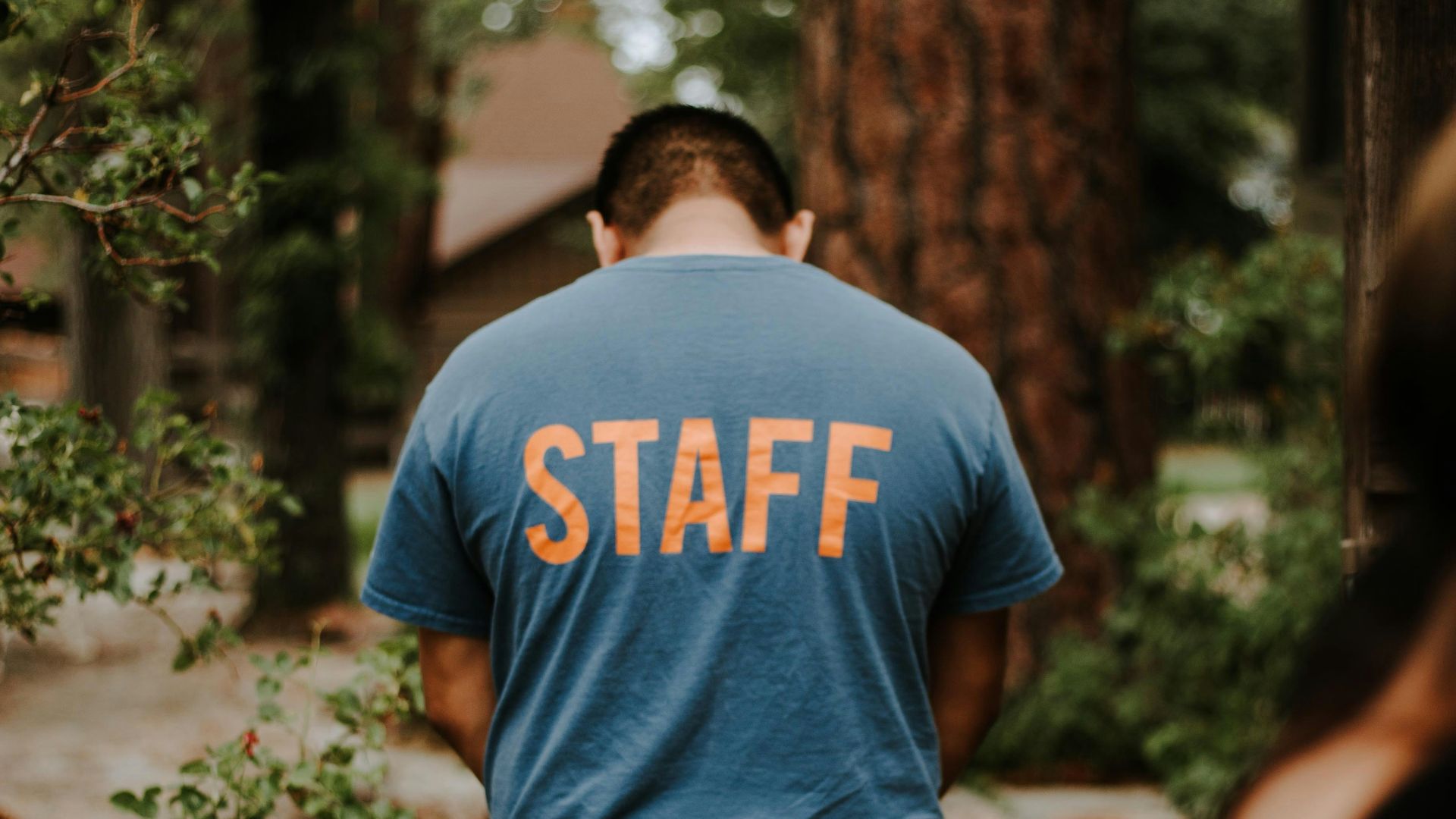 standing man wearing staff t-shirt near tree