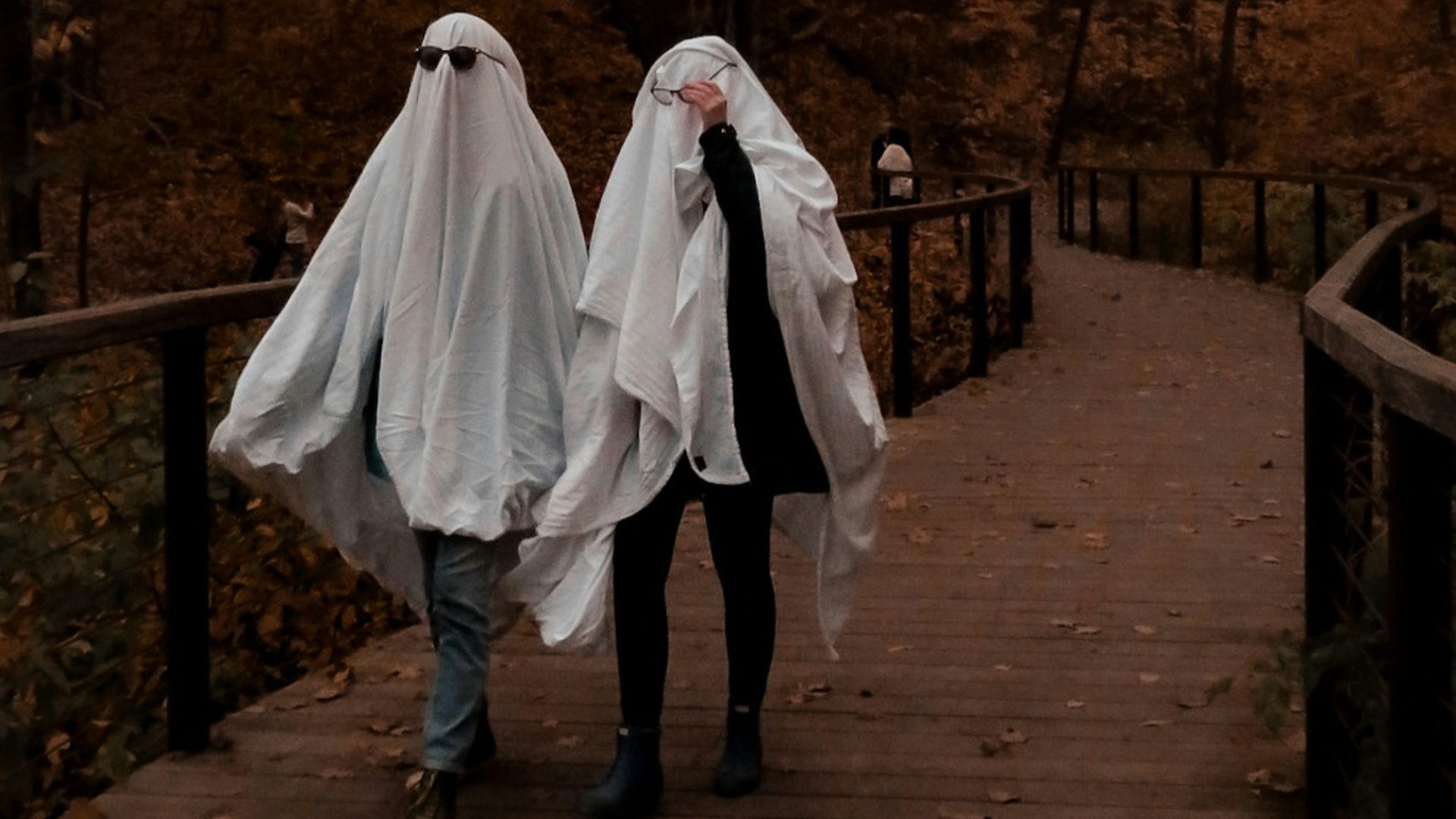 woman in white dress walking on brown wooden bridge