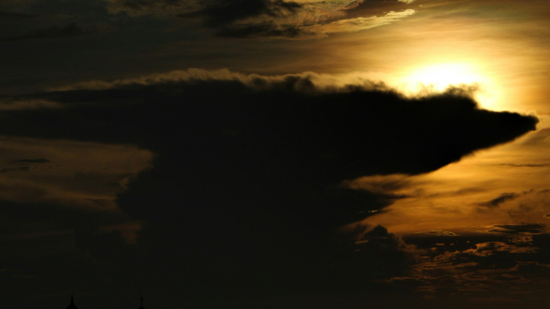 the sun is setting behind a cloud in the sky