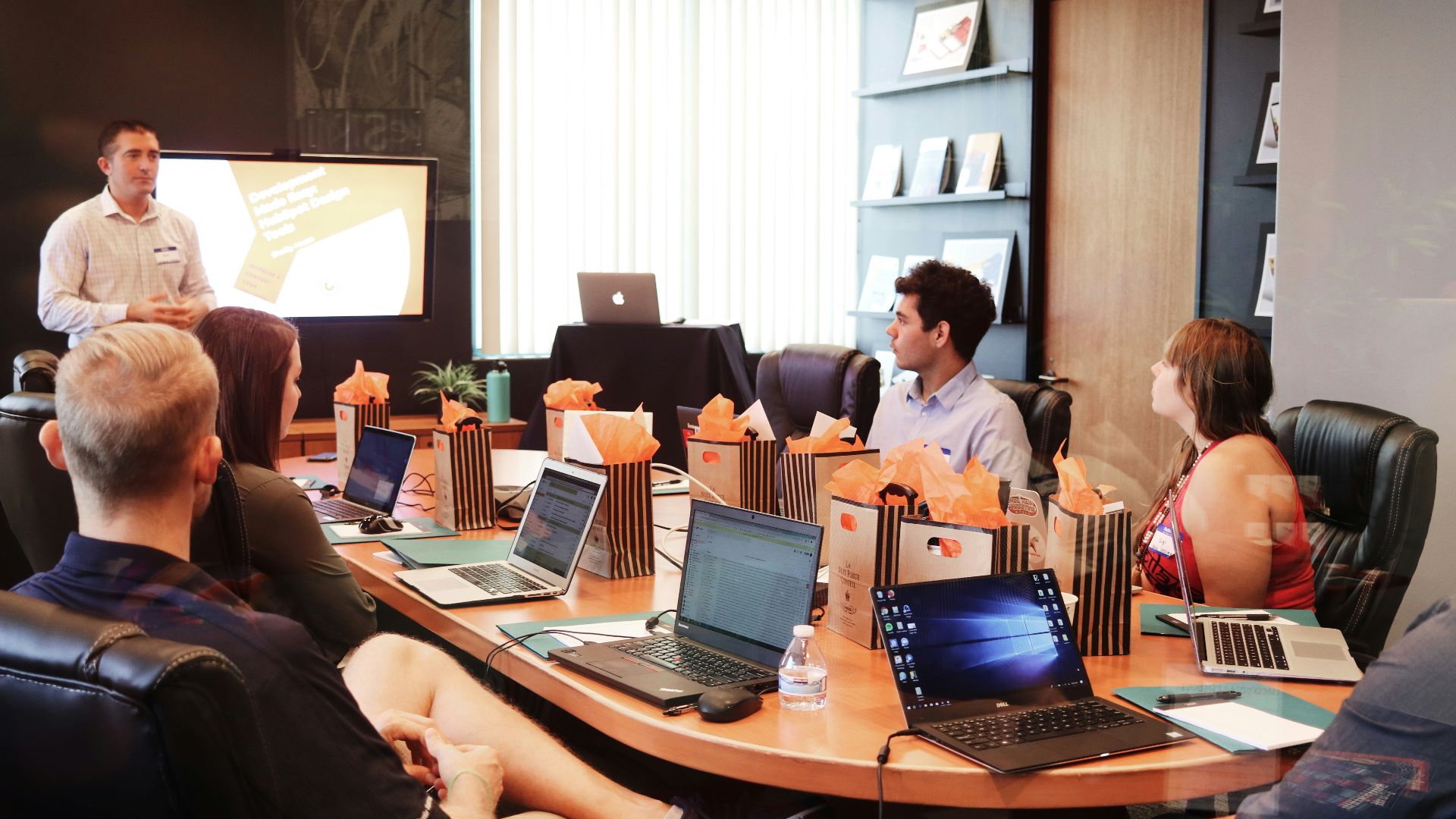 man standing in front of people sitting beside table with laptop computers