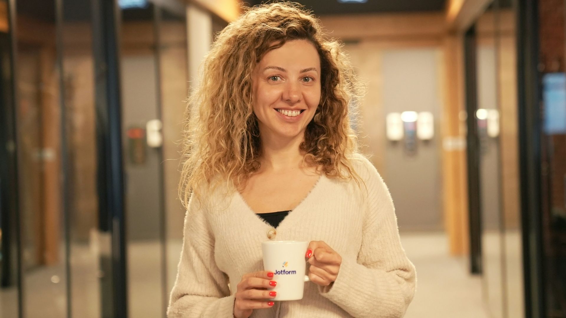 a woman holding a cup of coffee in a hallway