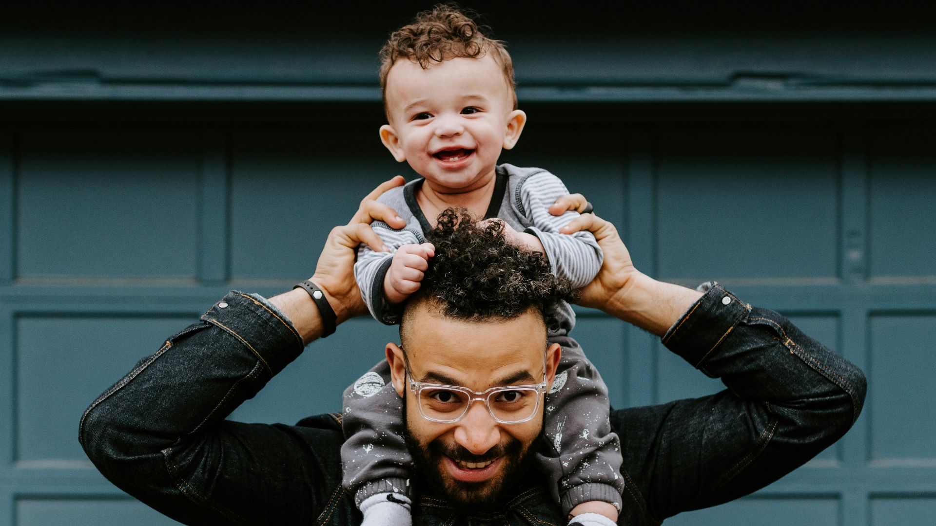 man in black leather jacket carrying boy in black leather jacket
