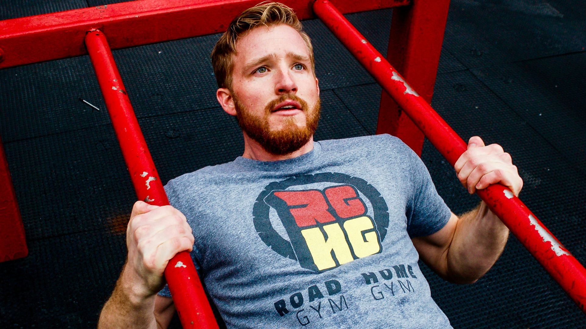 man in gray crew neck t-shirt holding red metal bar