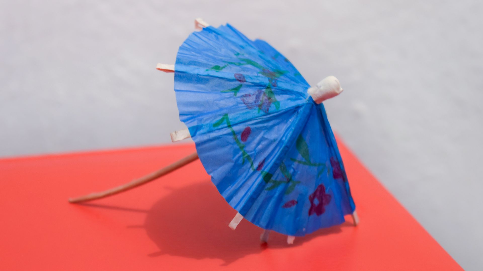 A blue cocktail umbrella with floral pattern.
