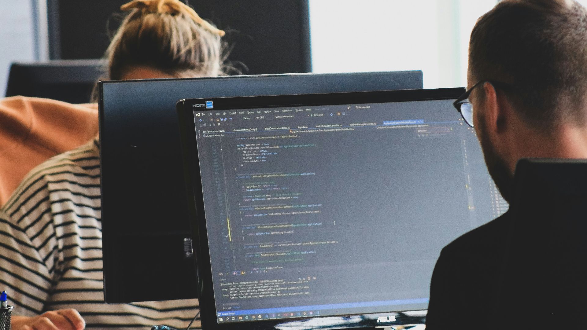 woman in black shirt sitting beside black flat screen computer monitor