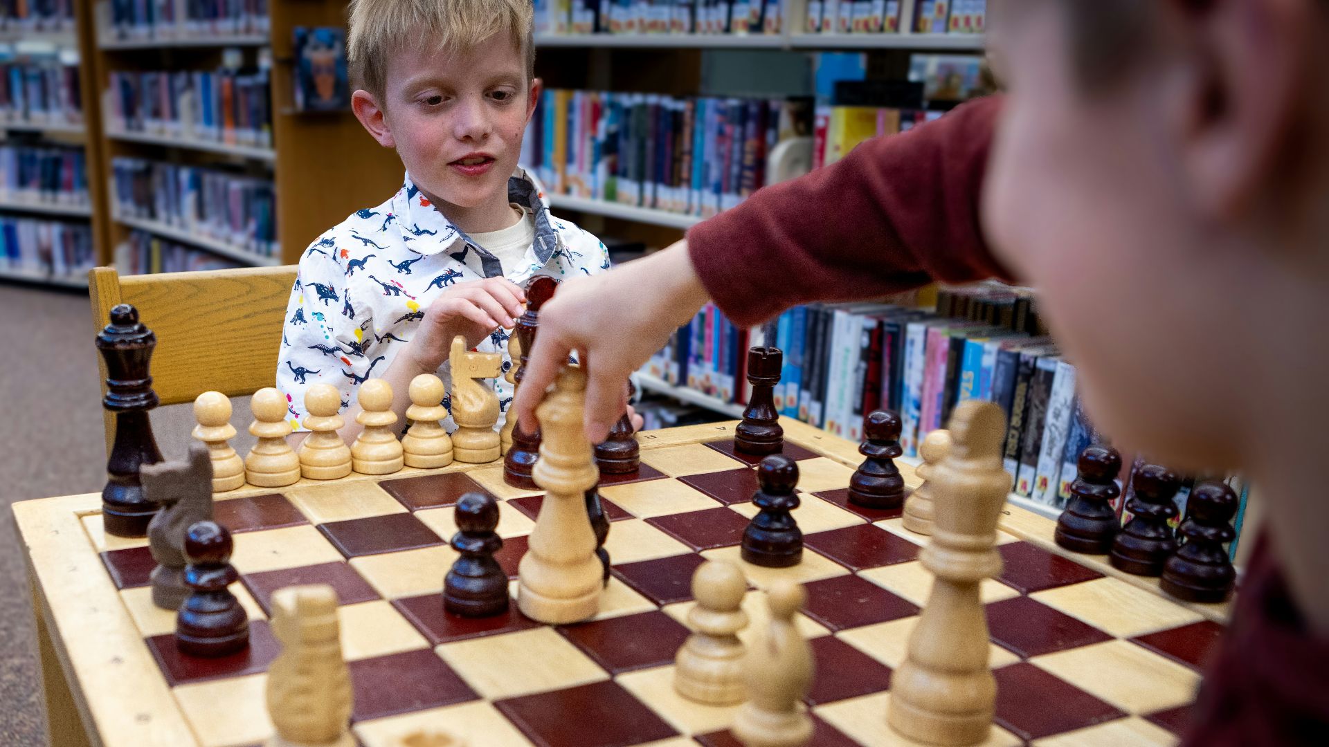 Children are playing a game of chess in a library.