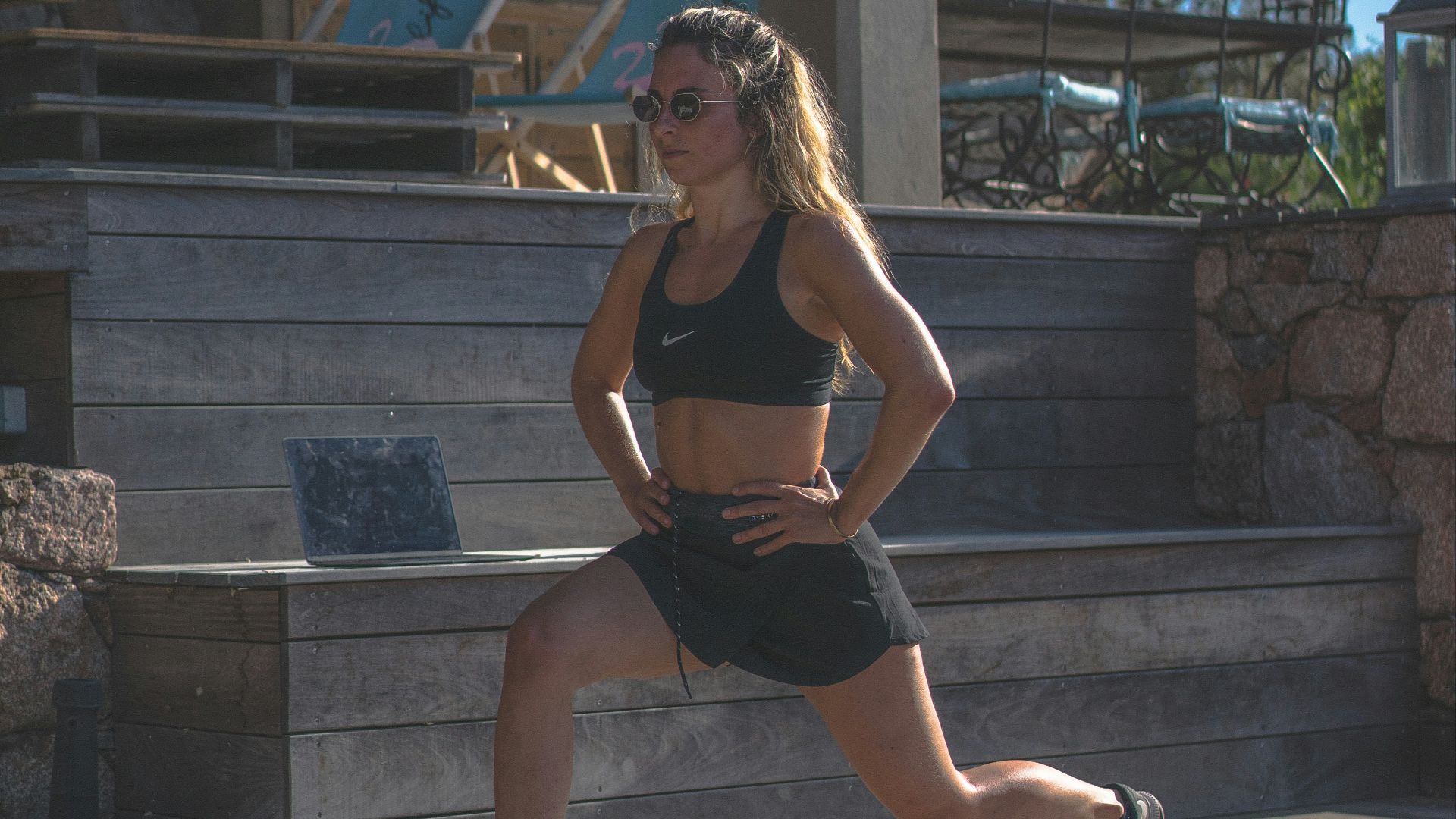 woman in black sports bra and black shorts sitting on concrete bench during daytime