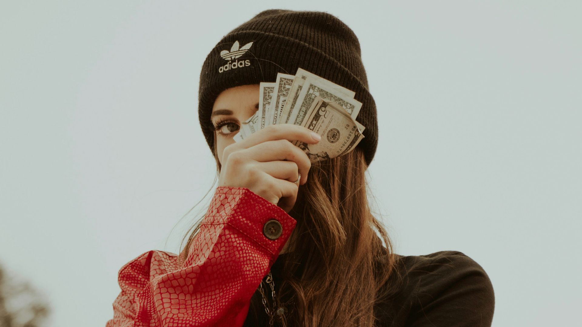 woman in black knit cap covering her face with her hand