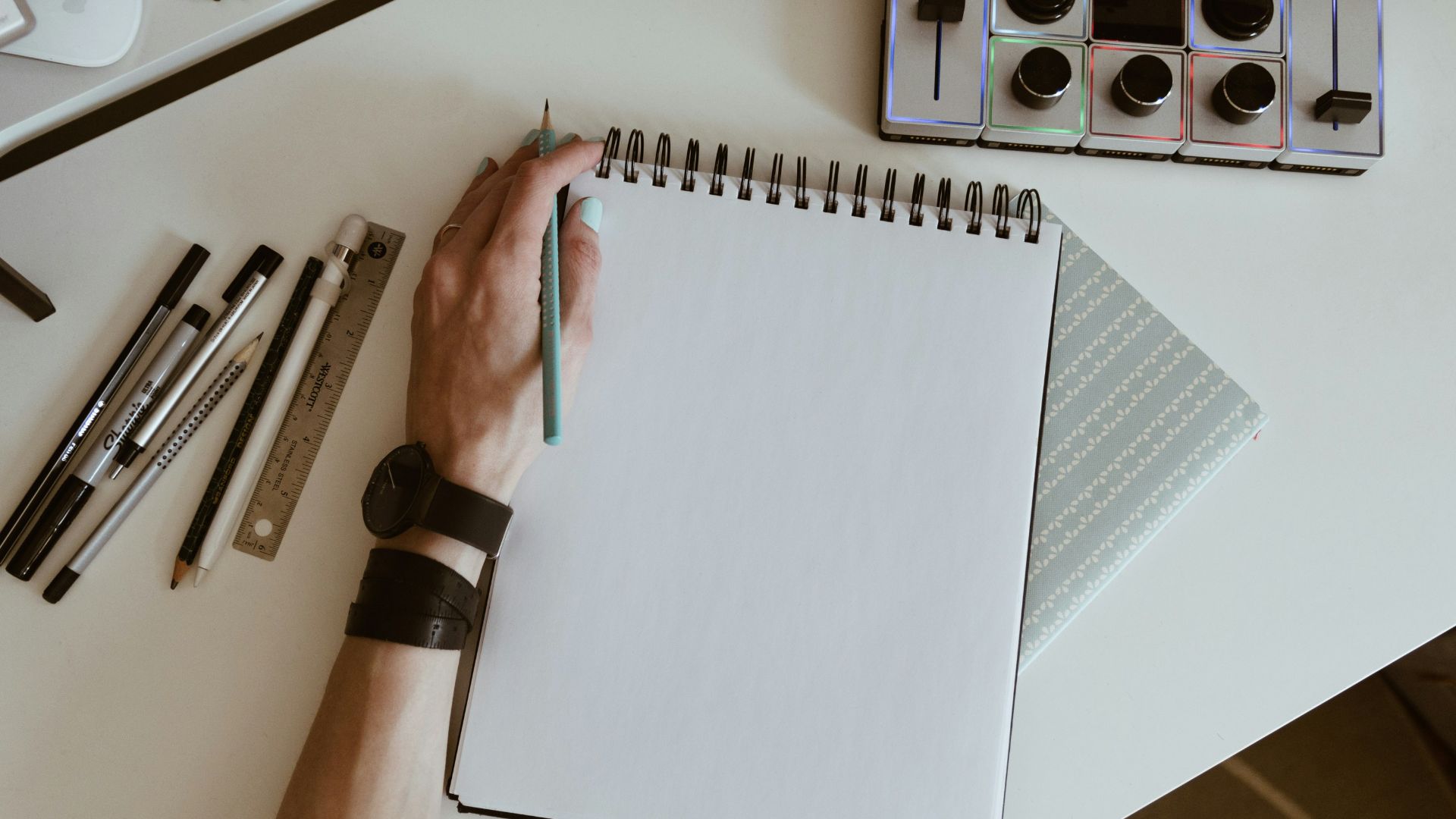 white spiral book with pens and watches