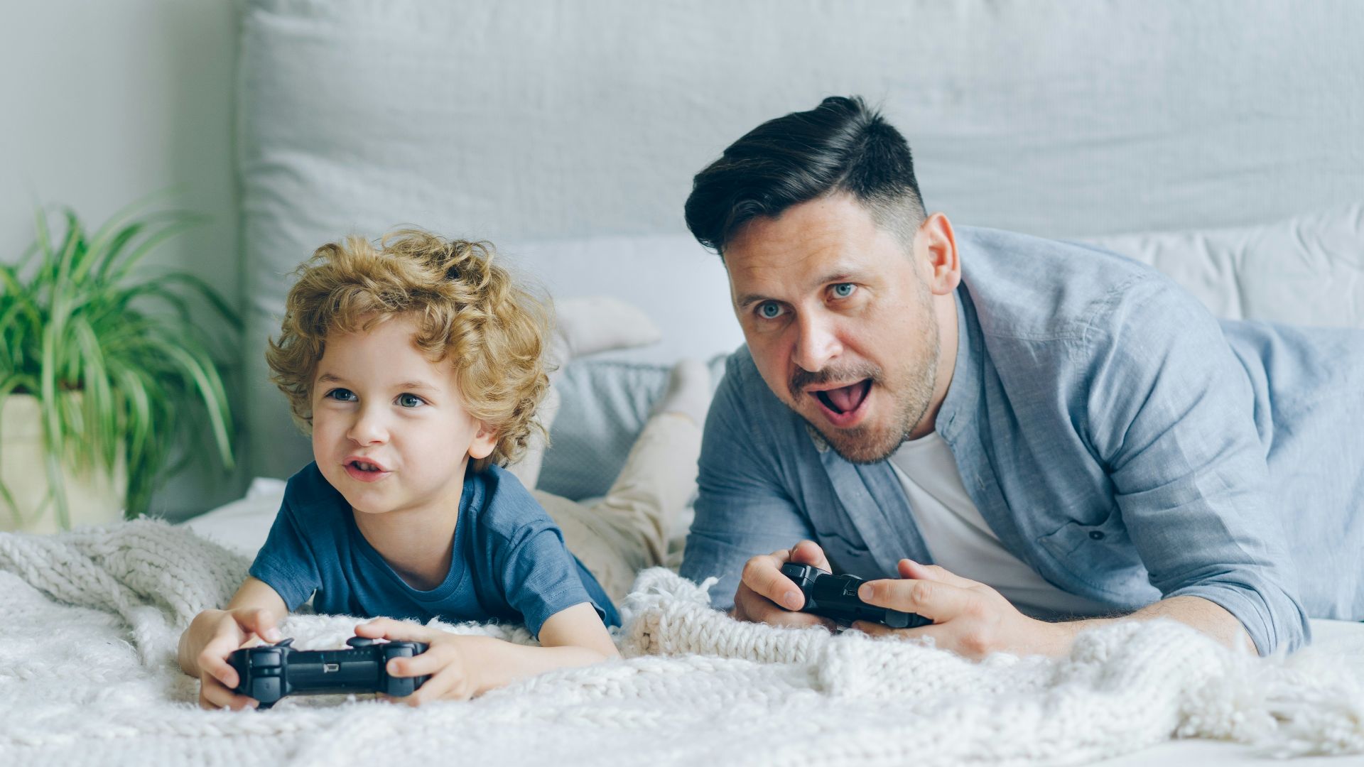 a man and a child laying on a bed playing a video game