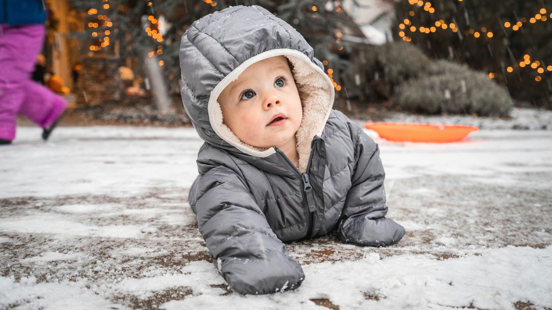 child in gray winter jacket lying on snow covered ground