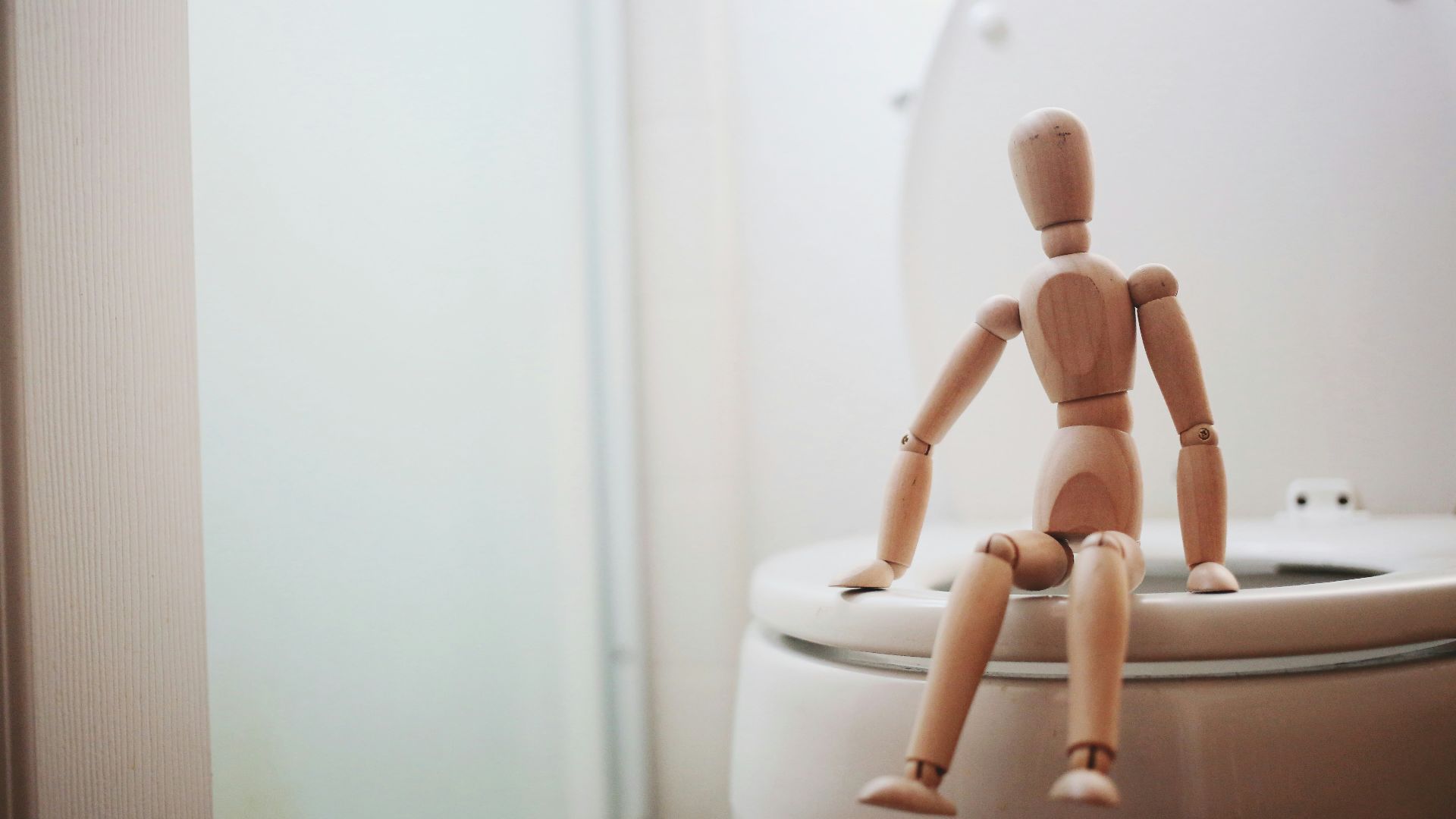brown wooden doll on white ceramic toilet bowl