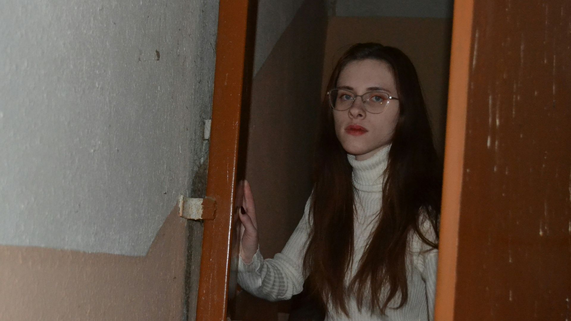 a woman with glasses standing in a doorway