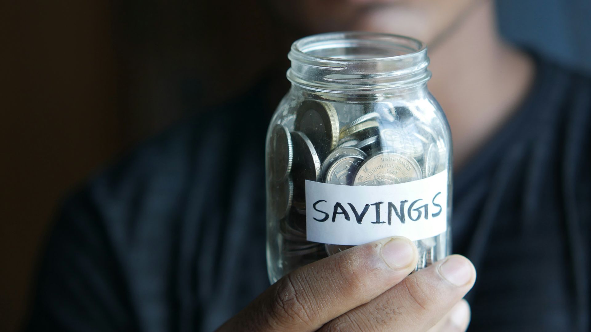 a man holding a jar with a savings label on it