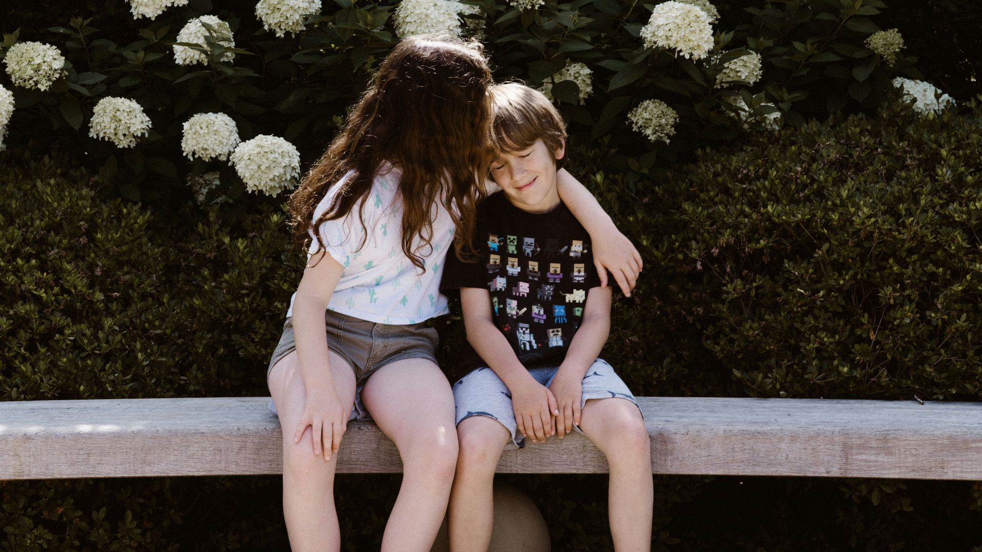 two toddler girl and boy sitting on concrete bench near outdoor during daytime