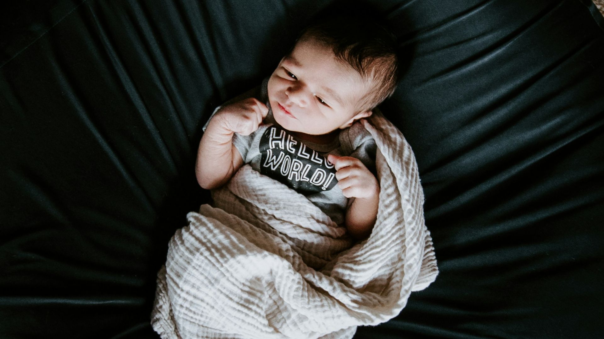 girl in white sweater and black pants lying on black round bed