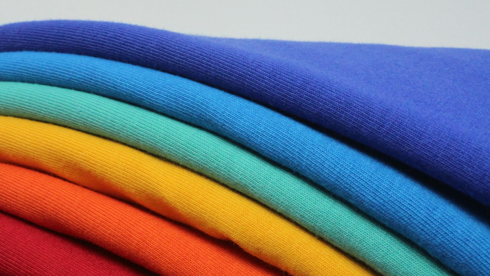 a stack of different colored t - shirts sitting on top of each other